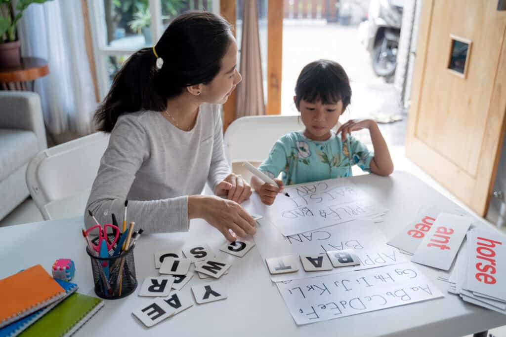 structured literacy - mother and daughter learning to read and write letters at home