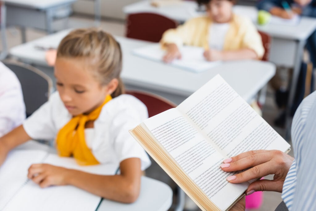 teacher reading to students at desk